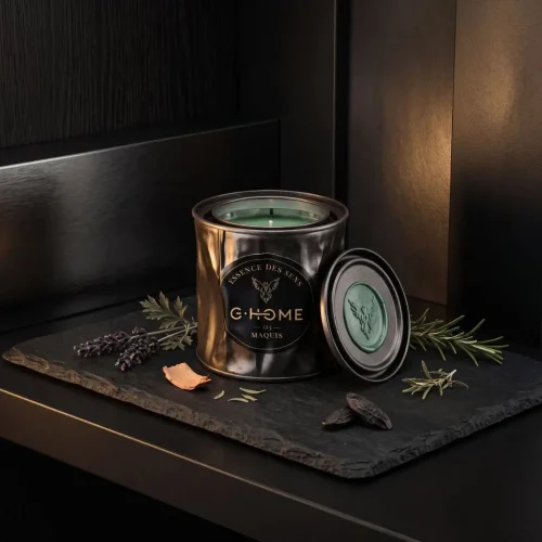 Bougie artisanale Maquis de la collection Essence des Sens dans son contenant en métal noir, accompagnée de lavande, romarin, cèdre et fève tonka.